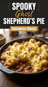 Shepherd's pie with meat and vegetables topped with mashed potatoes piped into three spooky ghost shapes with olive eyes.